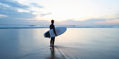 Person standing on the beach with surfing board