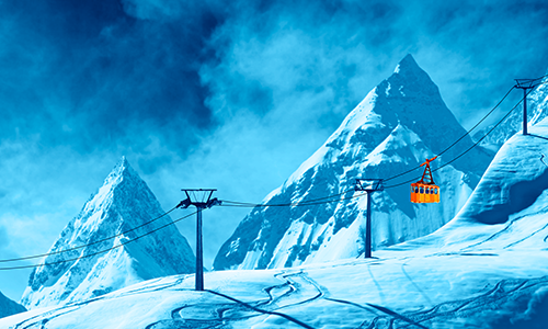 An orange cable car against the backdrop of snow mountains