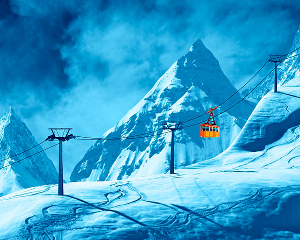 An orange cable car against the backdrop of snow mountains